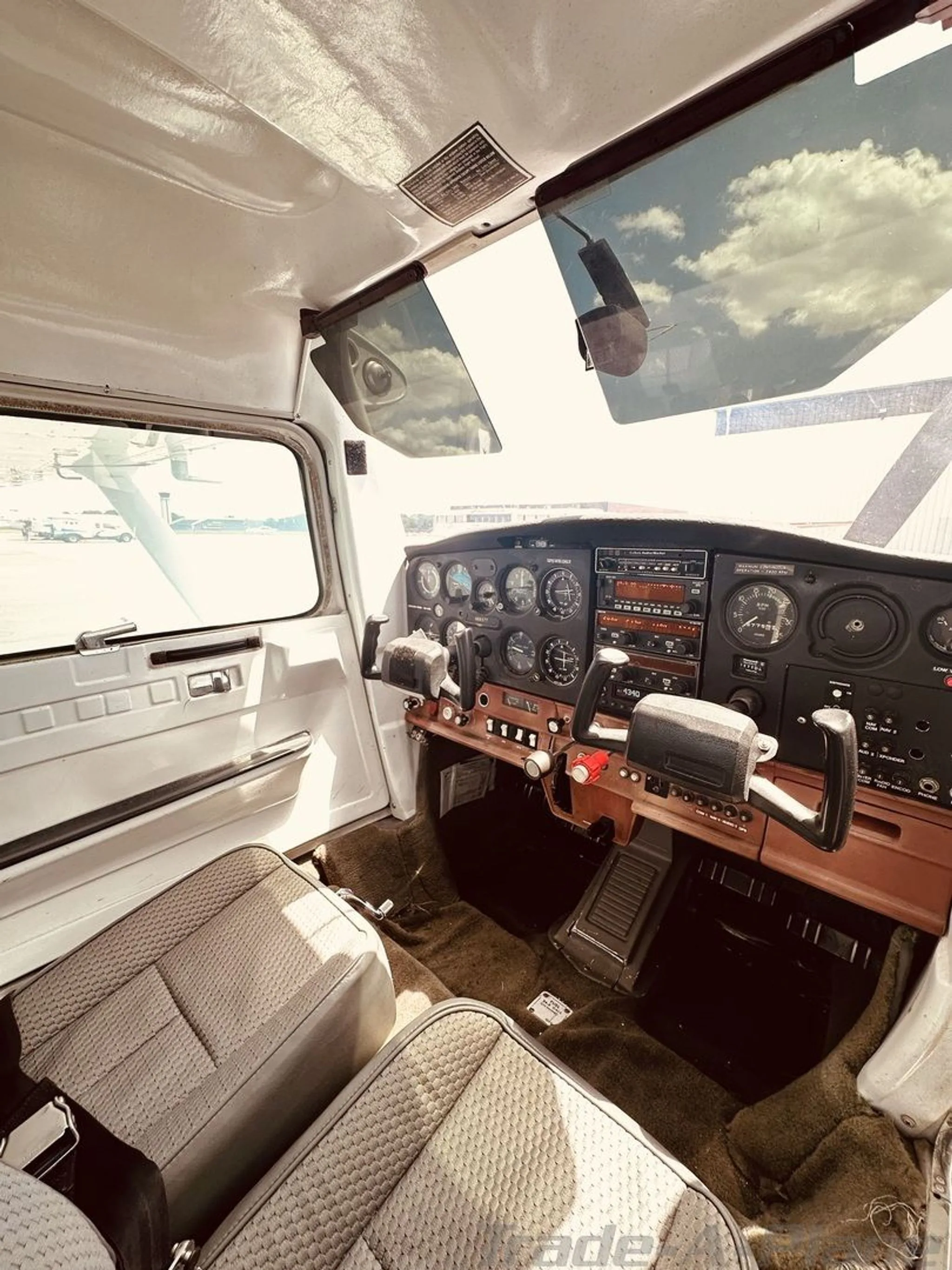 The cockpit of a Cessna 172, showing the instrument panel, yokes, and two front seats.