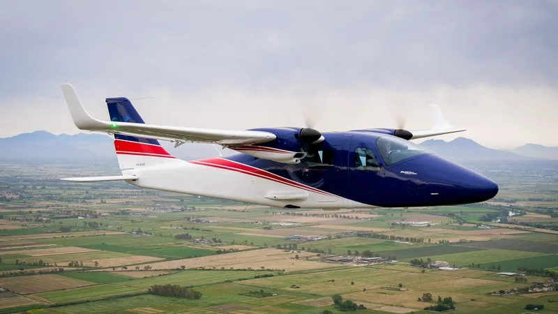 A blue and white Piaggio P.180 Avanti aircraft with a red stripe flying over green fields and mountains under a cloudy sky.