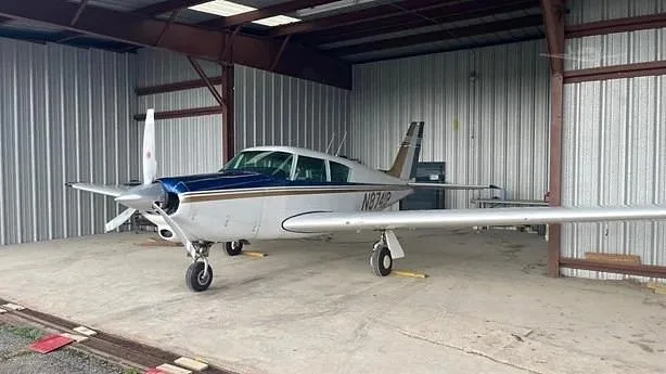 A white and blue single-engine aircraft, N8741P, parked inside a metal hangar.