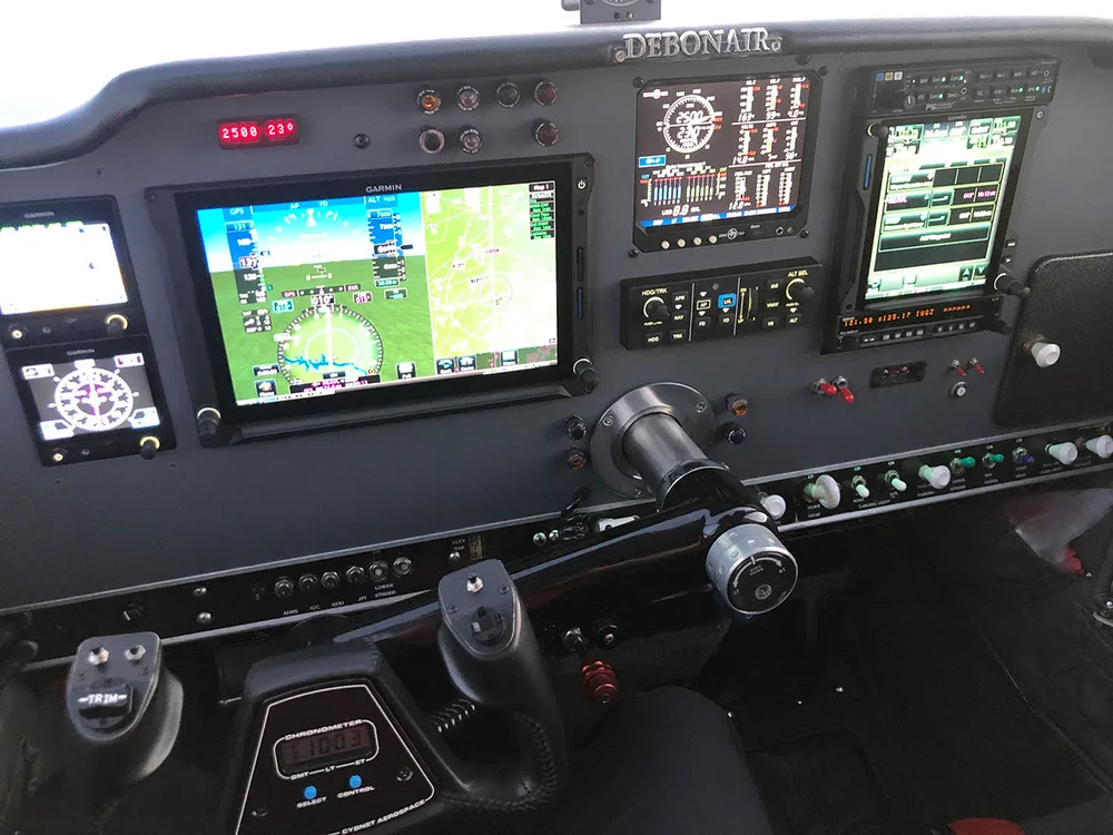The modern glass cockpit of a Beechcraft Debonair, featuring multiple Garmin displays and a control yoke.