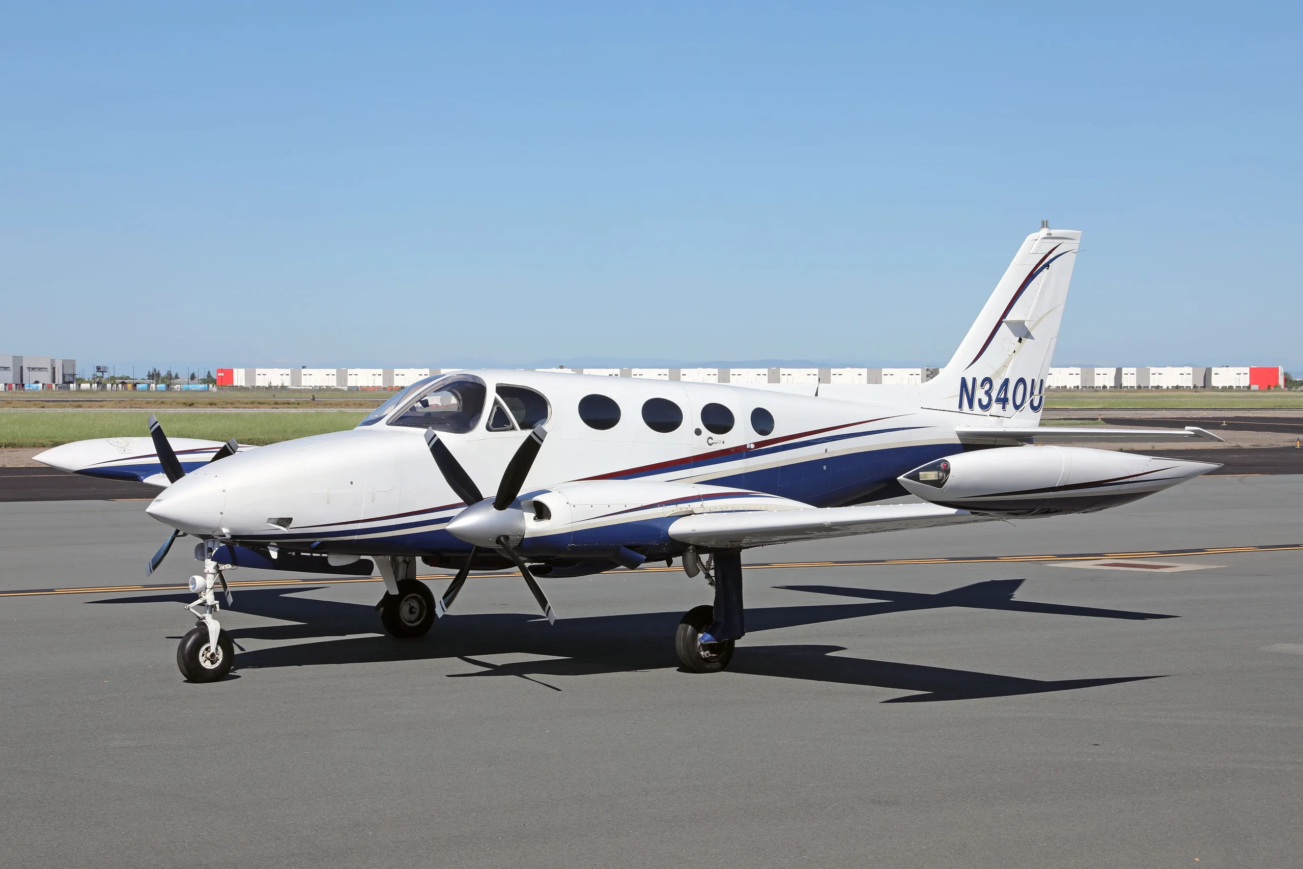 A side view of a white and blue Cessna 340 twin-engine aircraft with registration N340U on an airfield.