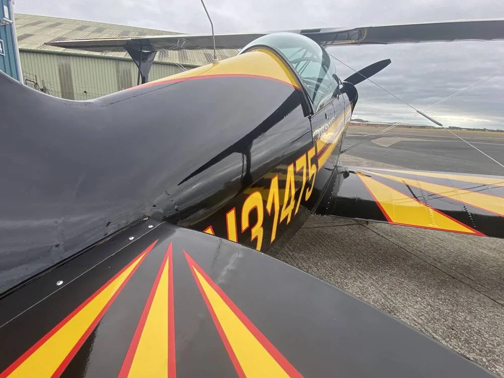A detailed view of the black and yellow fuselage and tail of the biplane N31475.
