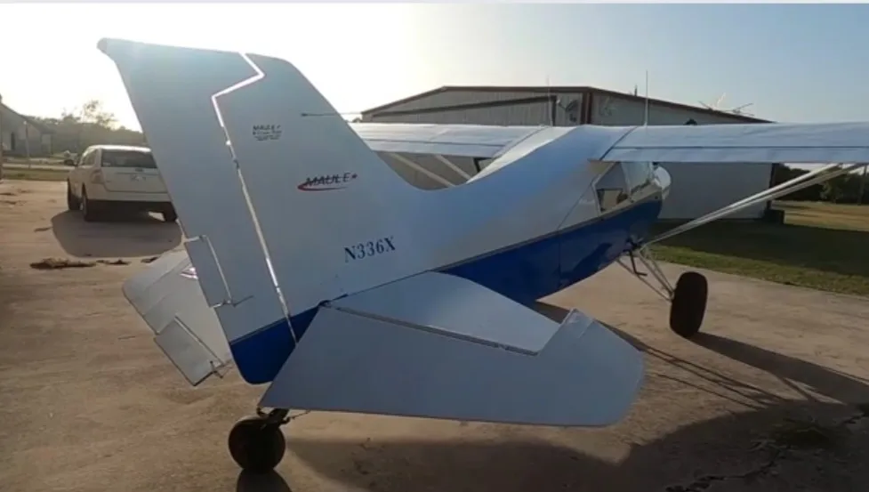 The tail section of a blue and white Maule aircraft, N336X, parked on an airfield.