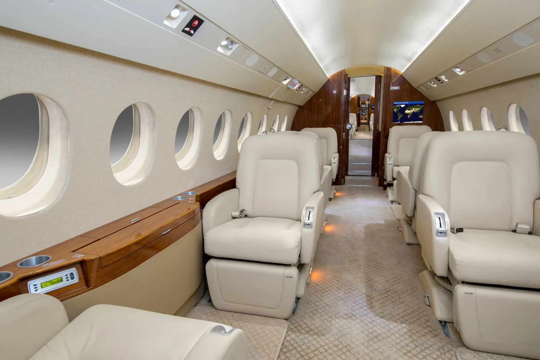 A luxurious aircraft cabin with light-colored leather seats and wood accents, looking towards the rear.