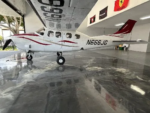 A Cessna 208 Caravan with a white and red paint scheme is parked in a hangar.