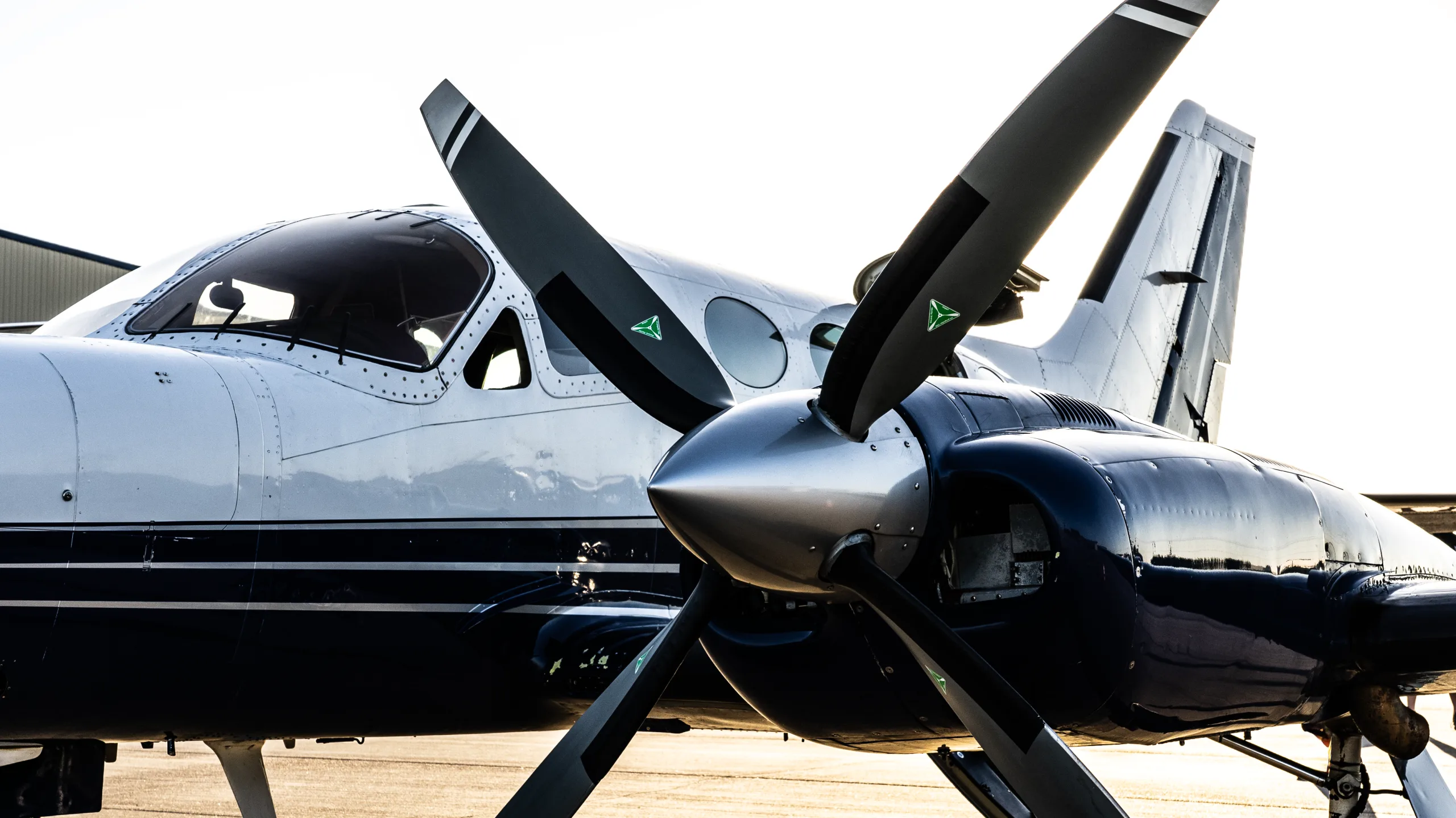 A close-up, front-quarter view of a white and dark blue twin-engine turboprop aircraft on an airfield.