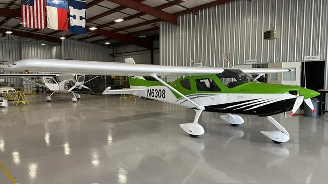 A full view of the N6308 Colt light sport aircraft with green, white, and black livery, parked in a hangar.