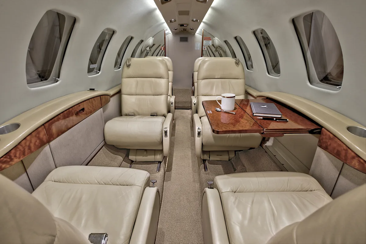 Aircraft interior with tan leather seats and wood accents.