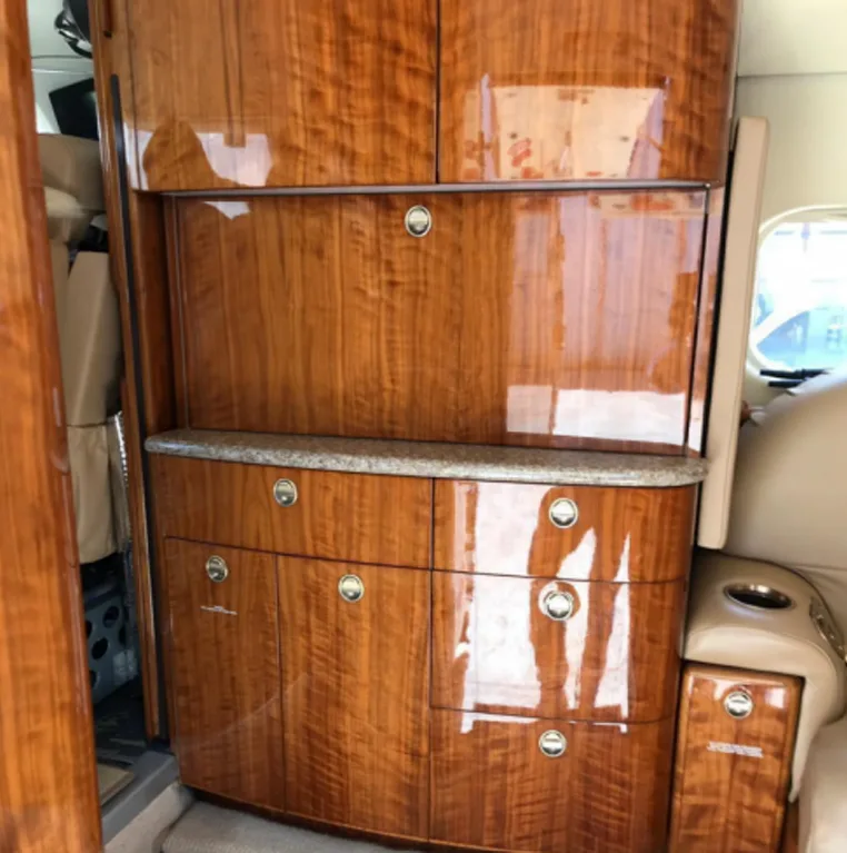 Detailed view of the highly polished, burled wood cabinetry and a small counter in the aircraft's interior.