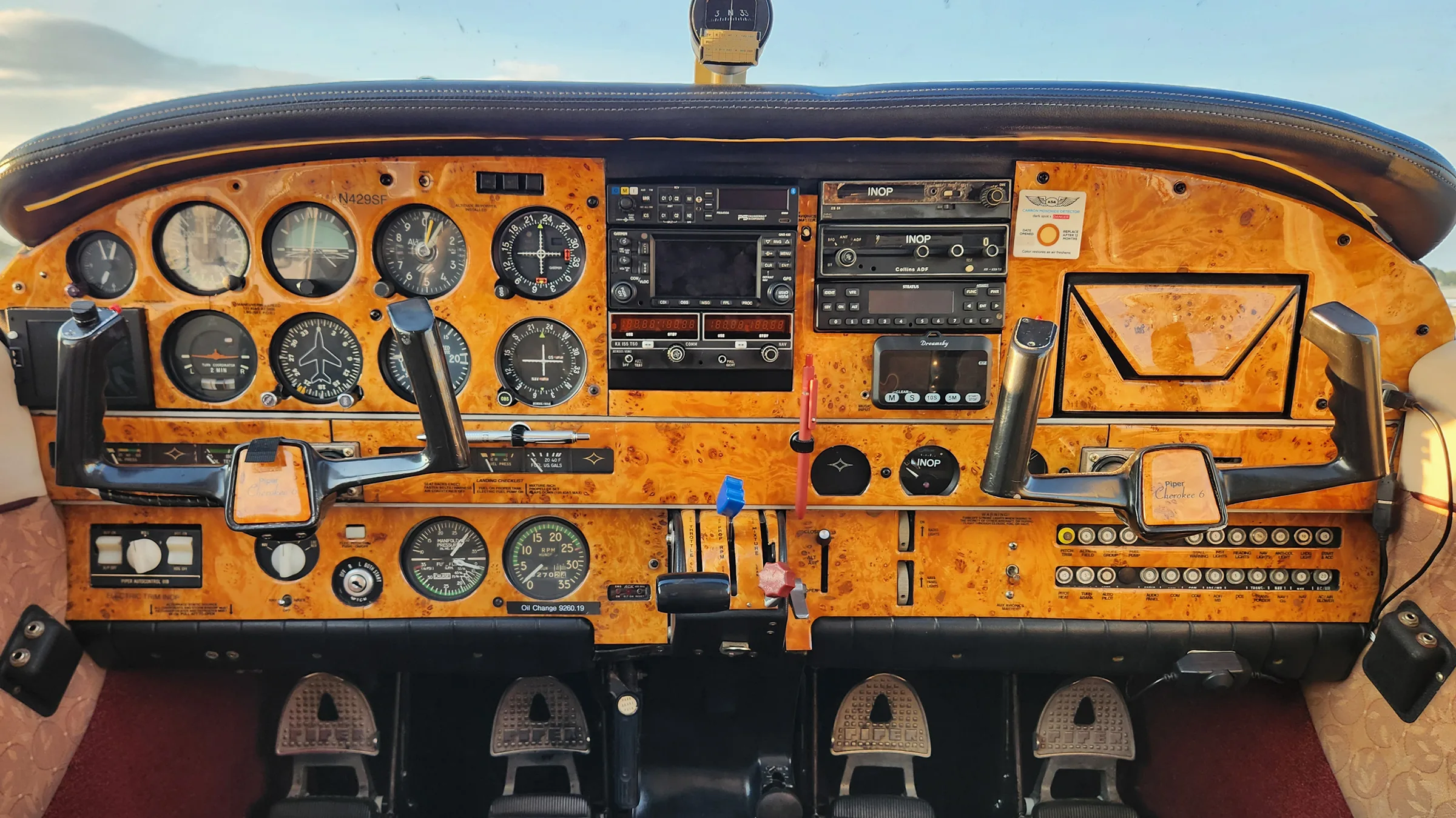 Close-up view of an aircraft cockpit featuring a wood-grain instrument panel with dual yokes and a full array of gauges and avionics.