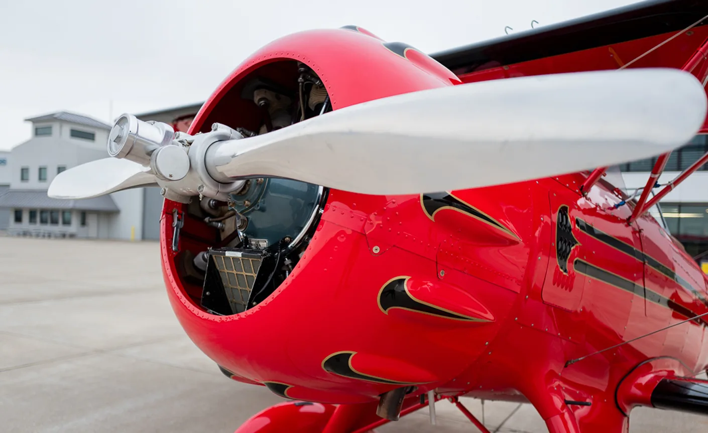 Close up of the engine and propeller of a red biplane.