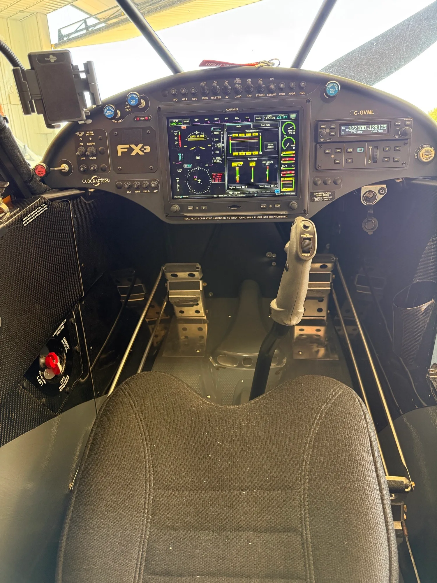The modern glass cockpit of a CubCrafters Carbon Cub EX-3, showing the instrument panel, stick, and rudder pedals.