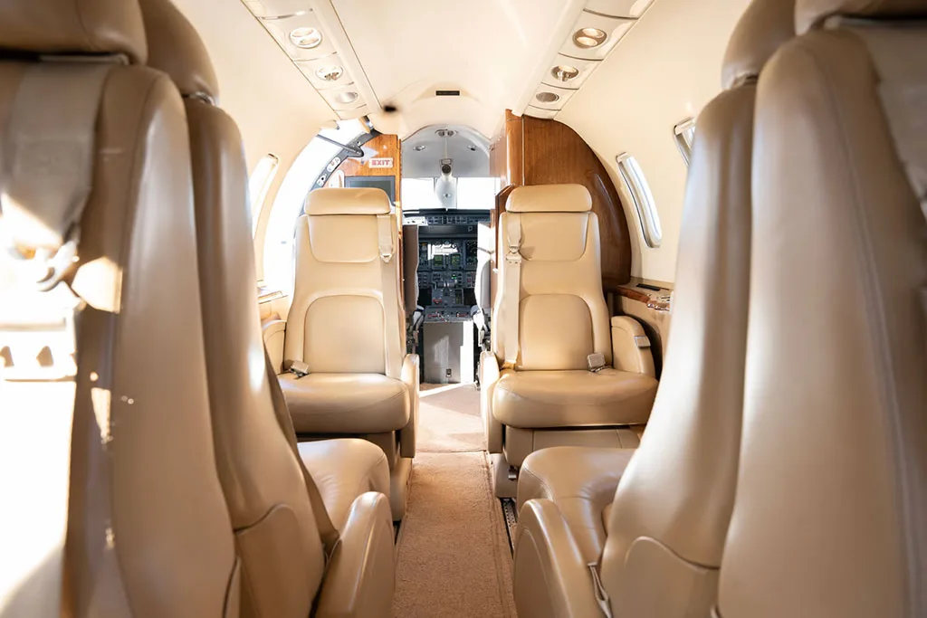 View from the rear of the cabin looking forward towards the cockpit, showing beige leather seats.