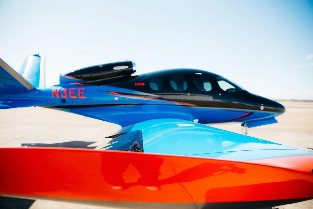 A close-up view of the blue and black Cirrus Vision Jet (N3EE) on an airfield.