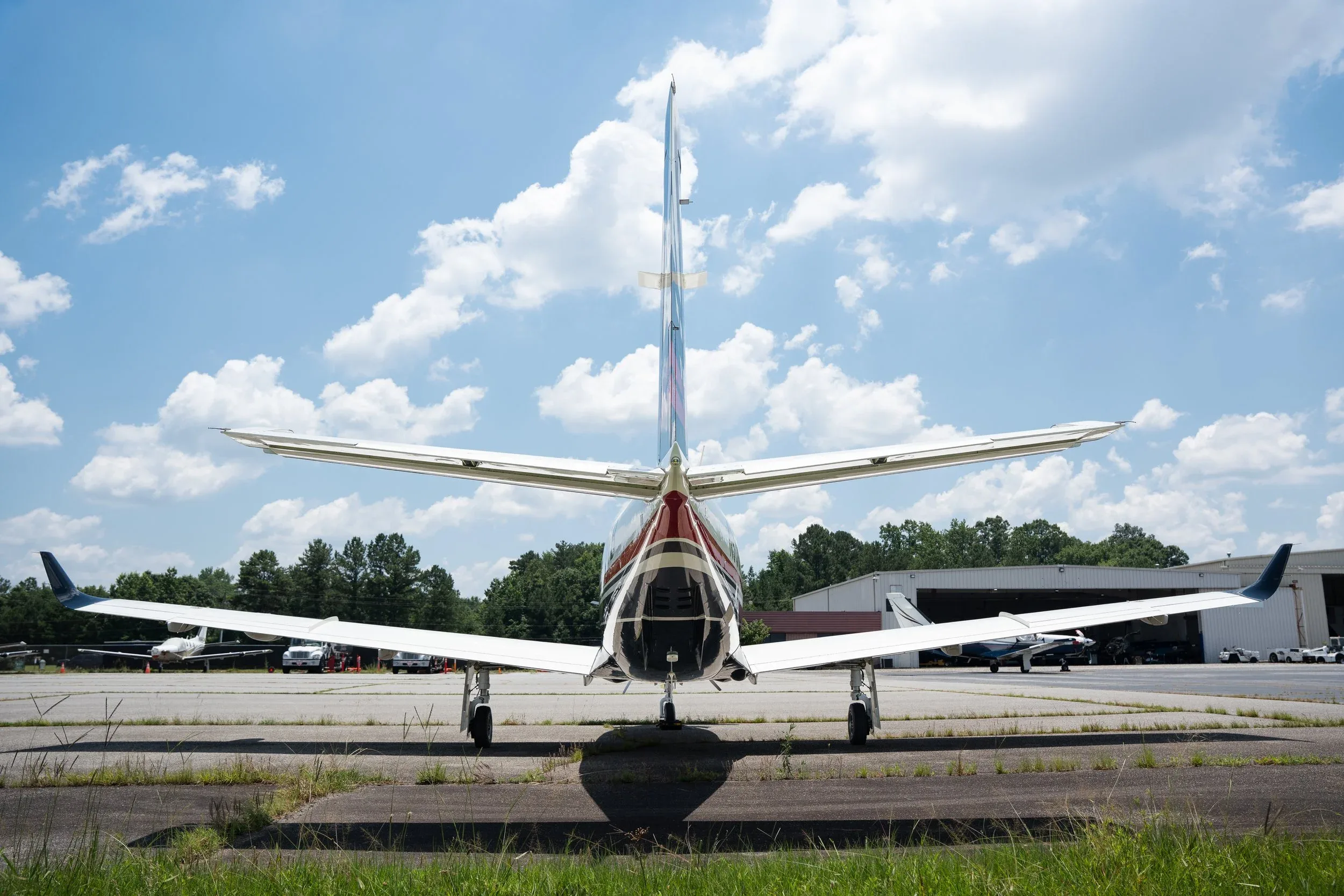 A rear view of a white and black TBM 960 aircraft with its tail and wings prominent, parked on an airport tarmac.