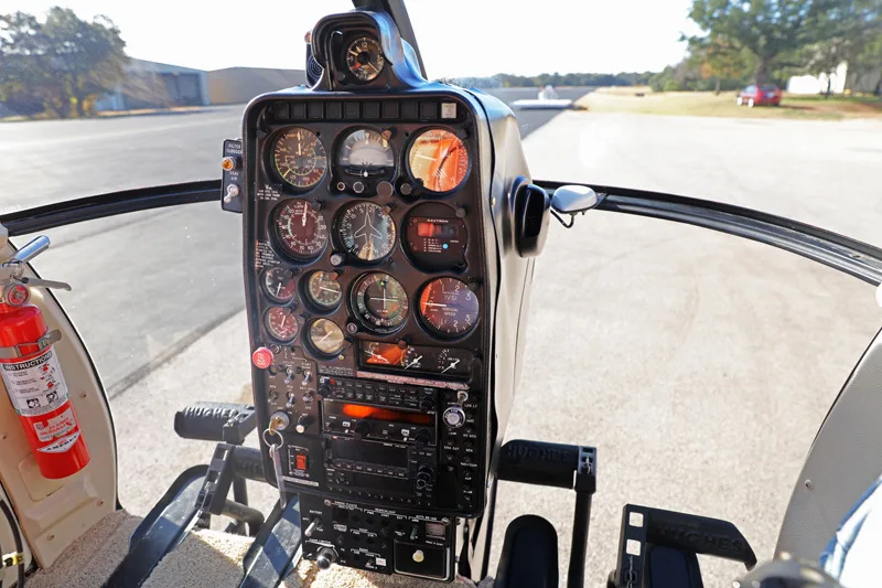 The instrument panel of a Hughes 369HS helicopter, with gauges and controls visible.