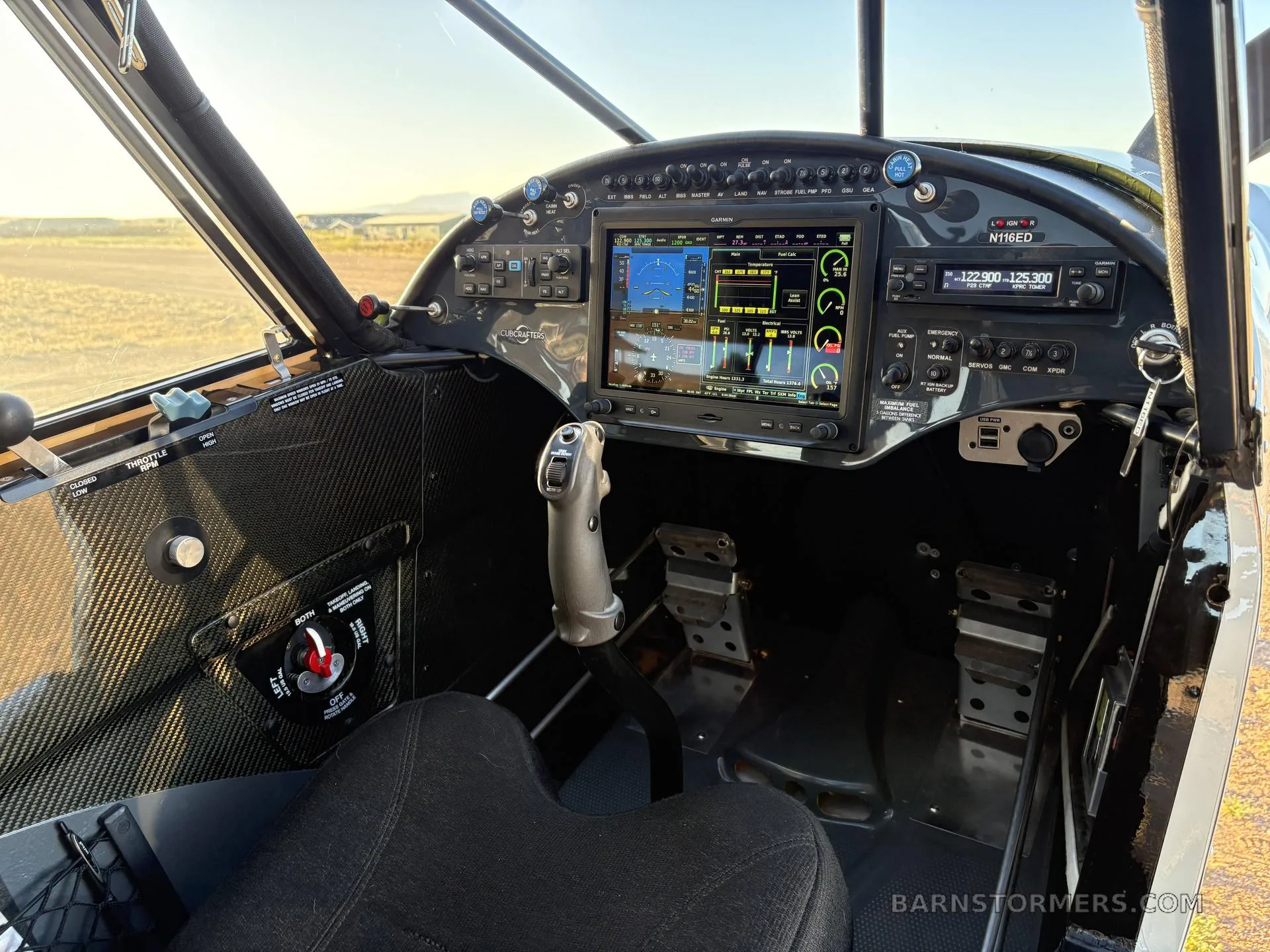The cockpit of a CubCrafters aircraft, featuring a modern glass panel display and a stick control.