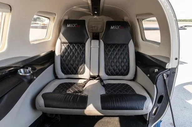 The rear cabin interior of a Piper M600, showing two black and grey quilted leather seats.
