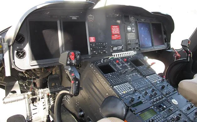 The cockpit of an AgustaWestland AW139 helicopter features multiple display screens and a complex control panel.