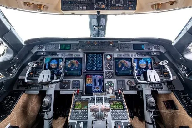 The modern cockpit features multiple digital displays, control yokes, and a central throttle quadrant.