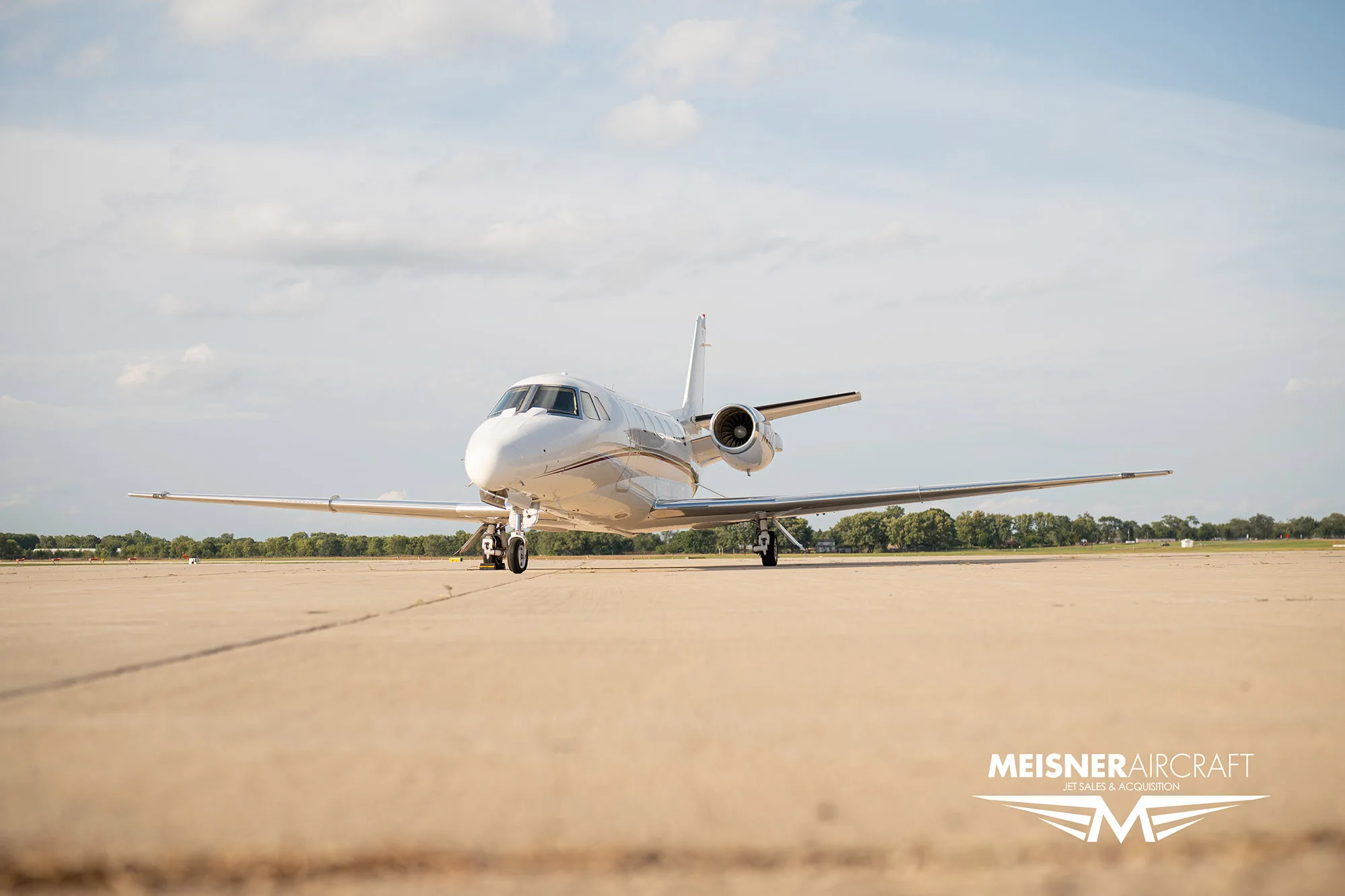 A white business jet with red stripes and registration N528AC viewed from the front on an airfield, with a 'Meisner Aircraft' logo.