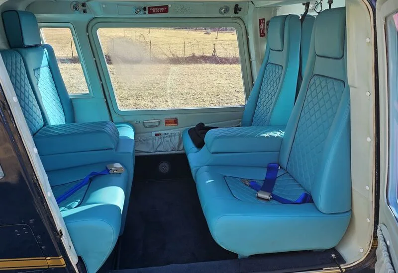 The interior of the helicopter features light blue leather seats with a diamond pattern.