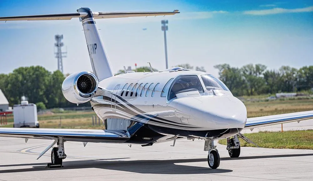 A front-quarter view of the white and blue Cessna Citation M2 jet, N178MP, on an airport tarmac.