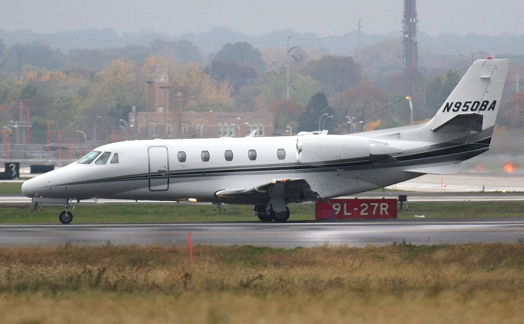 Side view of a white aircraft with tail number N950BA on the runway.