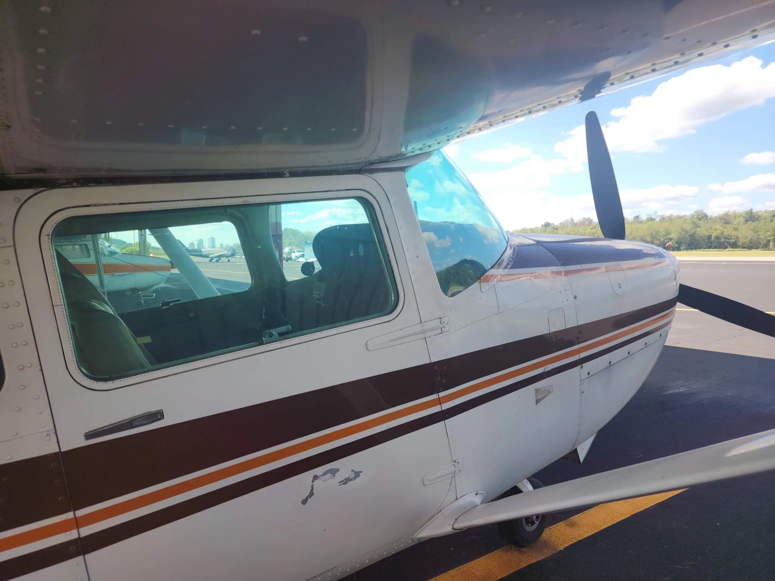 Side view of the cockpit and front fuselage of a white and brown Cessna Skylane RG II (N5019S) on the tarmac.