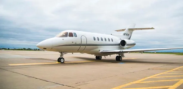 A white Hawker jet sits on the tarmac.