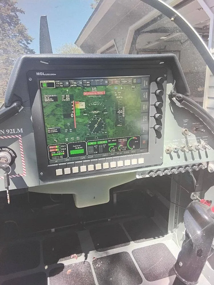 A view of a light aircraft's cockpit, featuring a large MGL digital flight display and surrounding switches and controls.