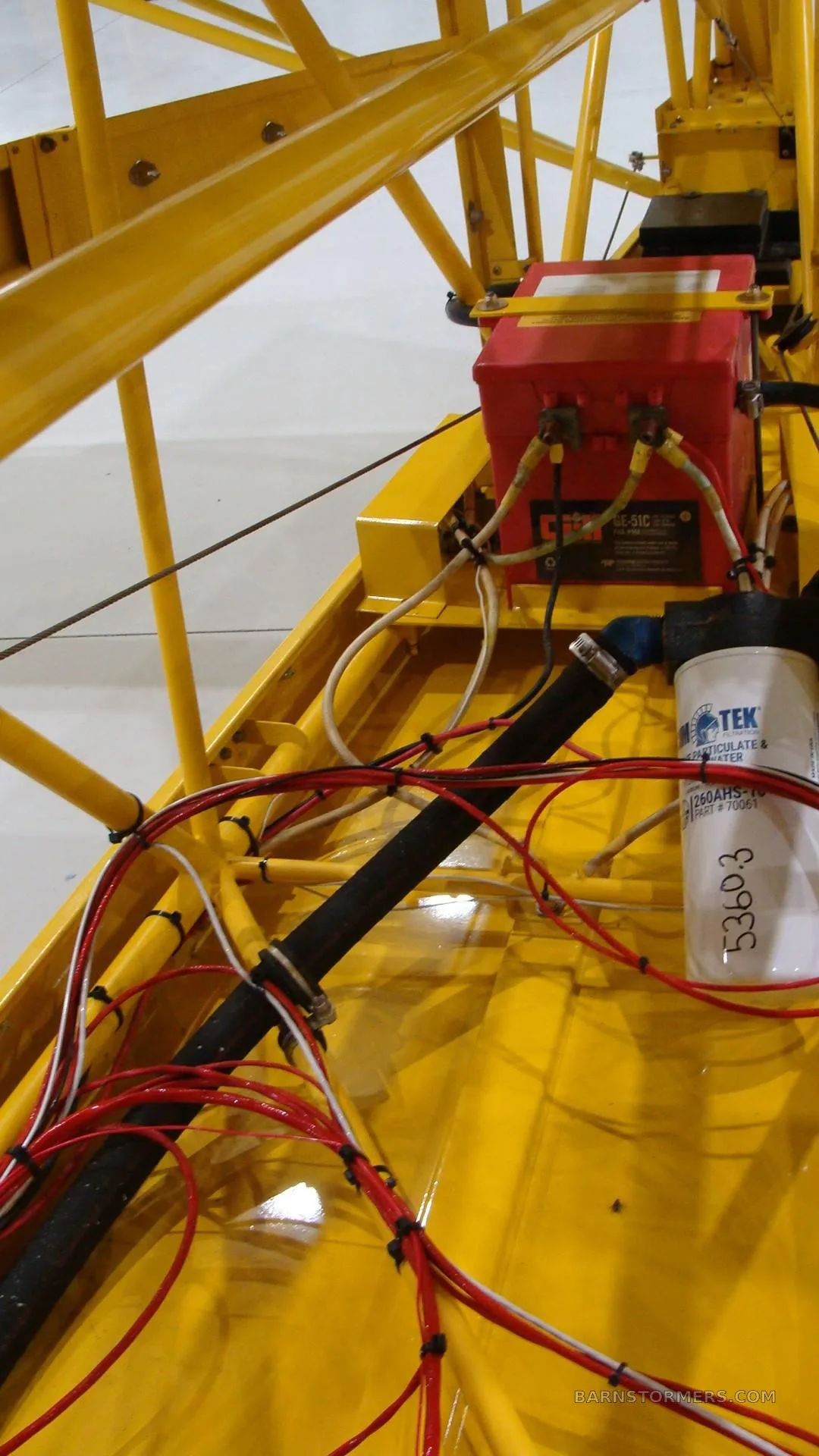 A close-up view of the yellow aircraft's internal structure, wiring, and a red battery box.