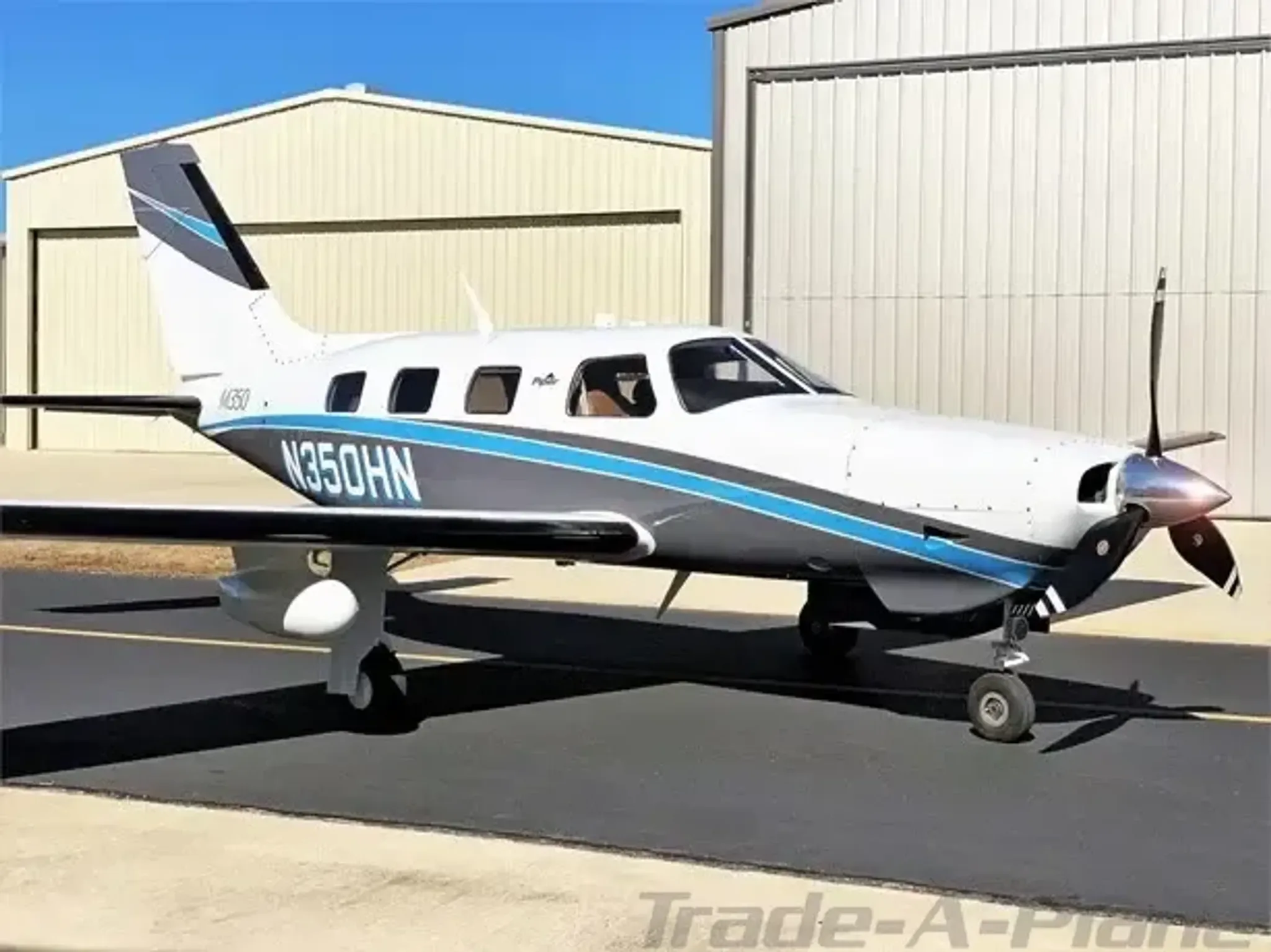 The aircraft is parked on the tarmac near a hangar.