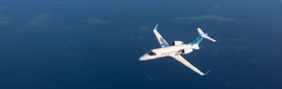 A white and blue jet aircraft flying over the ocean.