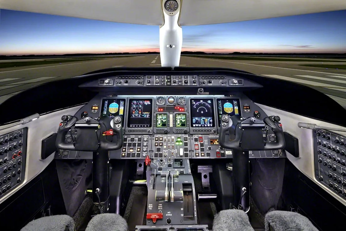 The cockpit of a modern business jet with multiple digital displays and control yokes, overlooking a runway at sunset.