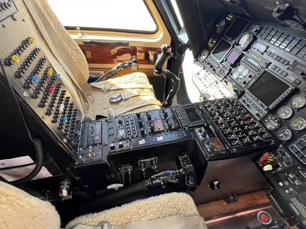 A close-up view of the helicopter's cockpit showing the pilot's controls and instrument panel.