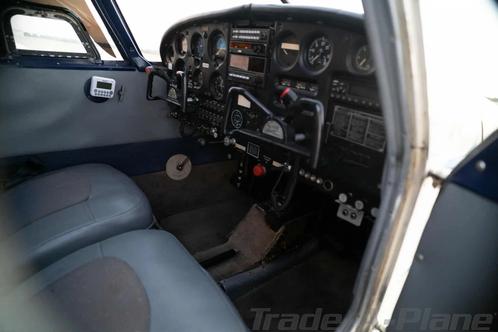 A view of the aircraft cockpit showing the instrument panel, controls, and front seats.