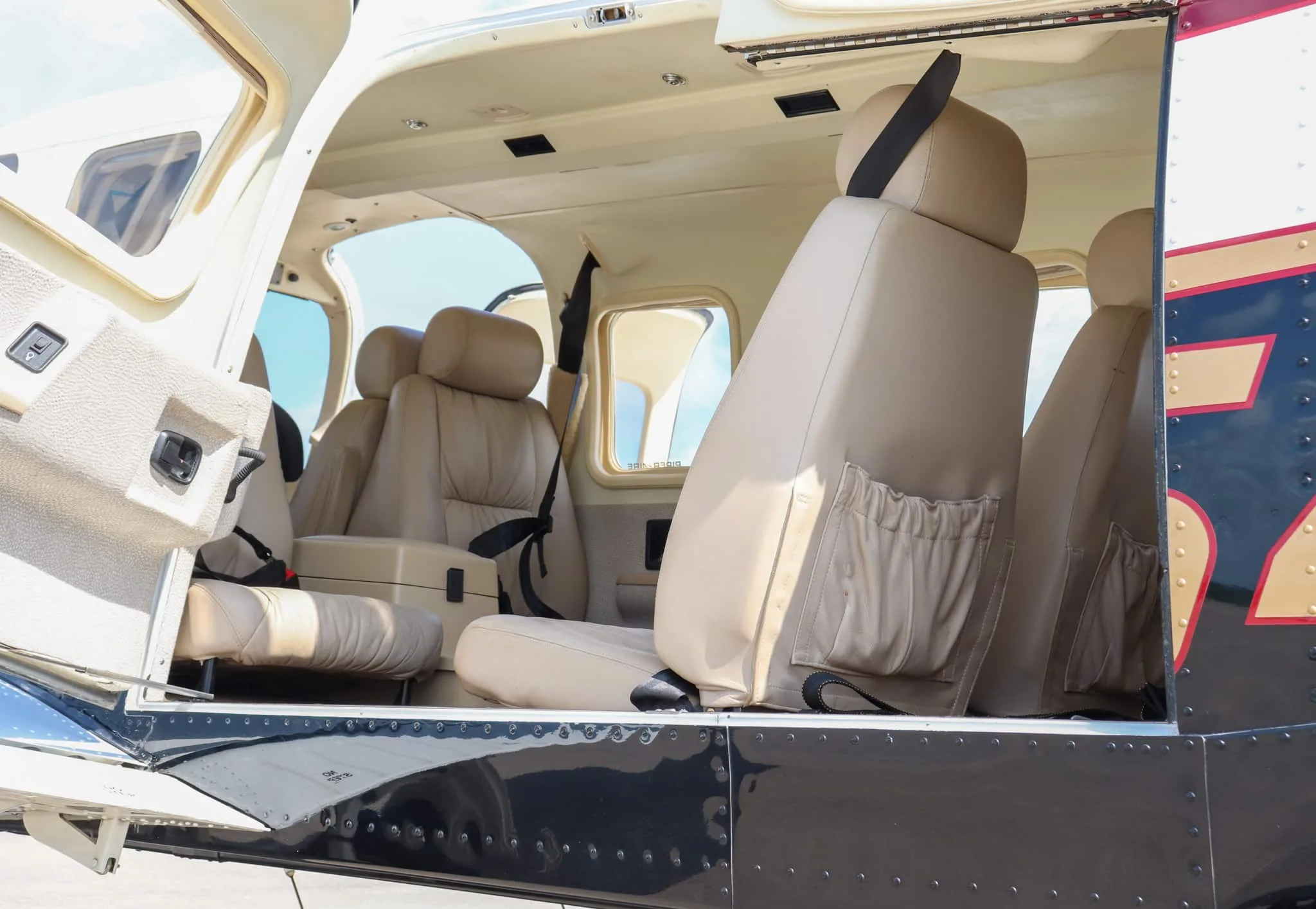 View into the aircraft cabin through an open door, showing light brown leather seats and the interior.