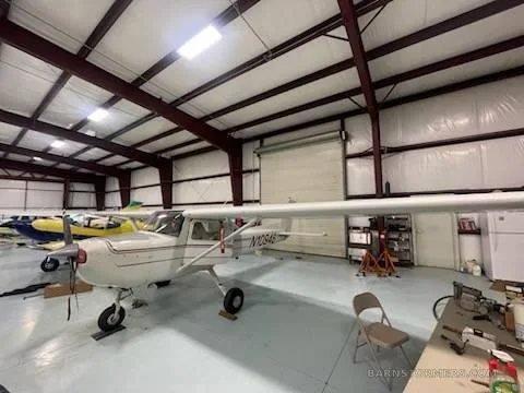 A white Cessna 150/152 type aircraft with registration N10946 is parked in a hangar, viewed from the front right.