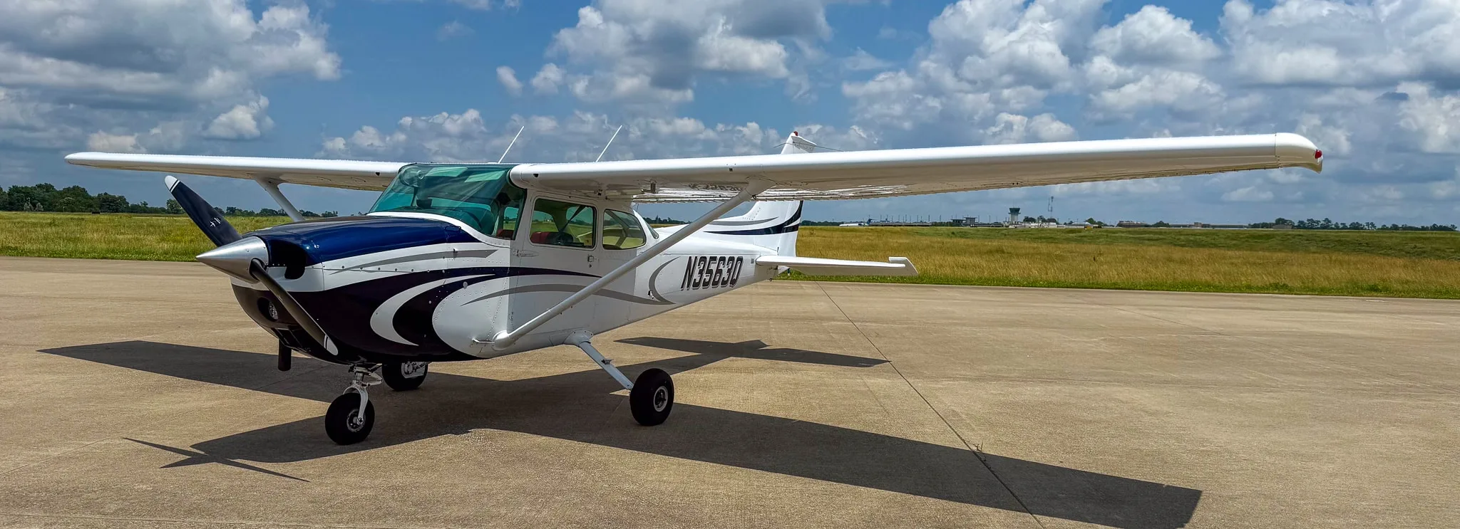 Front-left view of a white and blue Cessna 172 with registration N3563Q on an airfield under a partly cloudy sky.