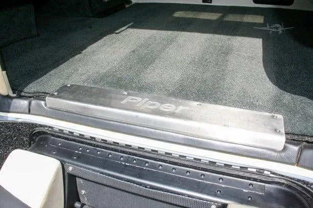 A close-up view of the Piper M600 SLS cabin floor, showing a metallic step plate with "Piper" embossed on it and dark grey carpeting.