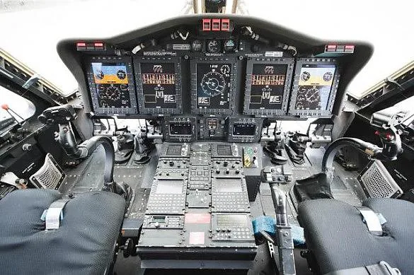 The modern cockpit of a helicopter, featuring multiple digital display screens and a central control panel.
