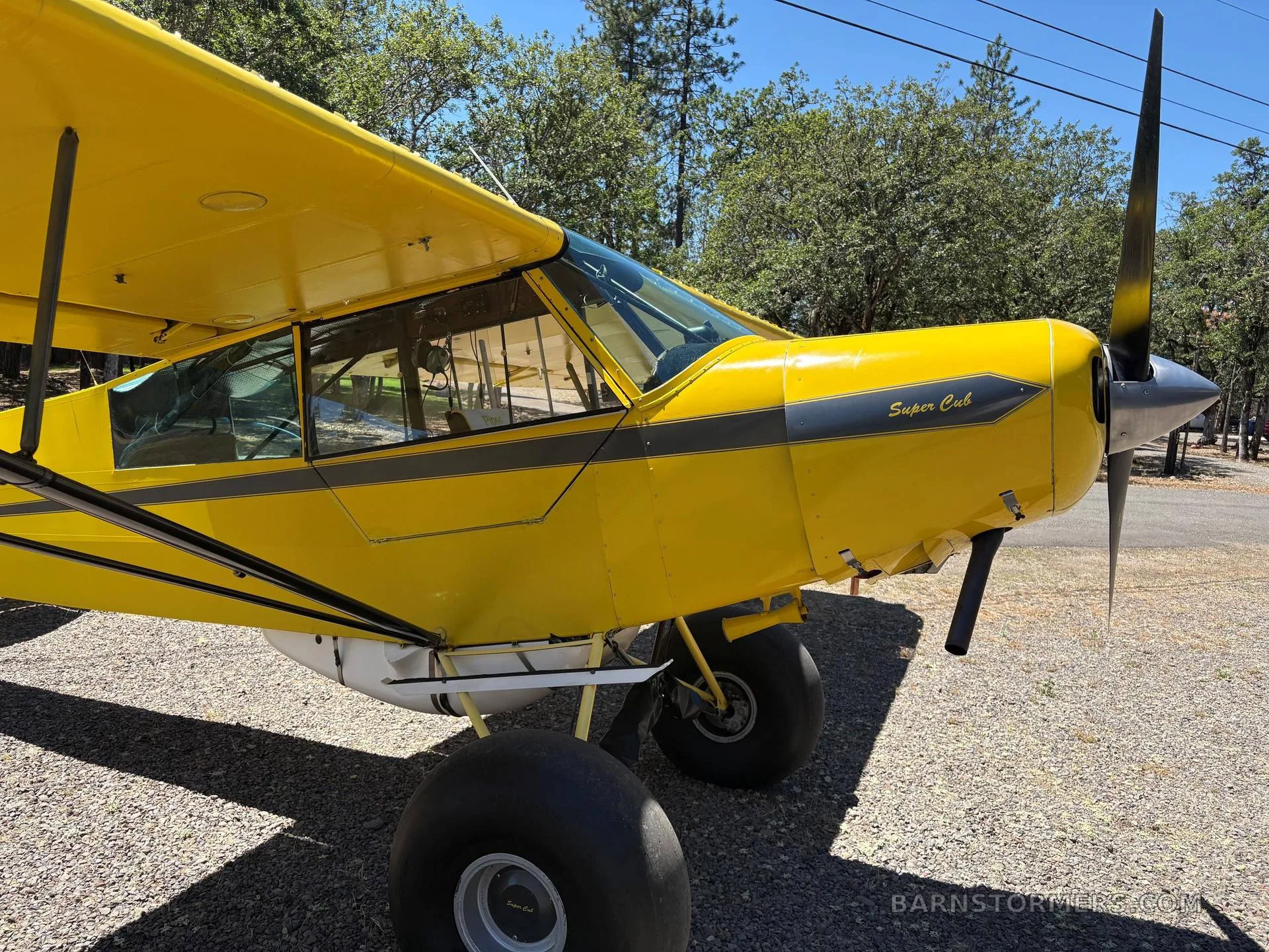 A close-up of the nose and propeller of a yellow Piper Super Cub, showing the "Super Cub" lettering and black stripe.