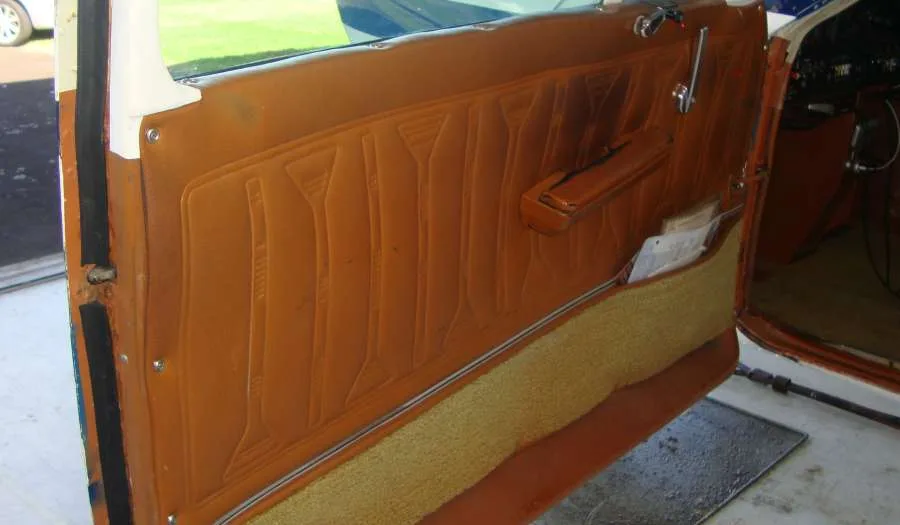 A close-up of an aircraft's brown patterned interior door panel with a storage pocket.