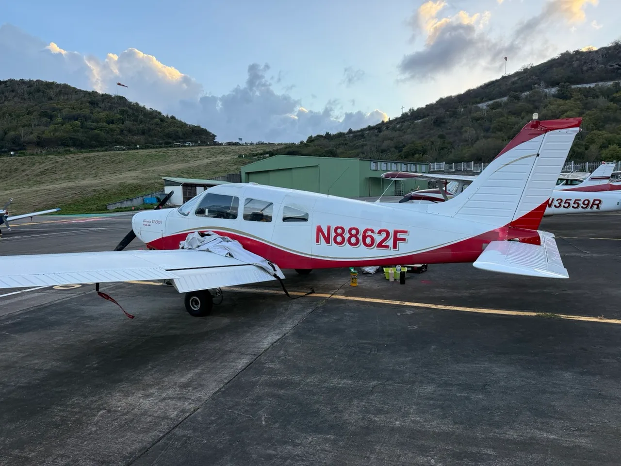 A white and red Piper Cherokee Warrior 160 HP aircraft (N8862F) parked on an airfield, viewed from the left-rear.