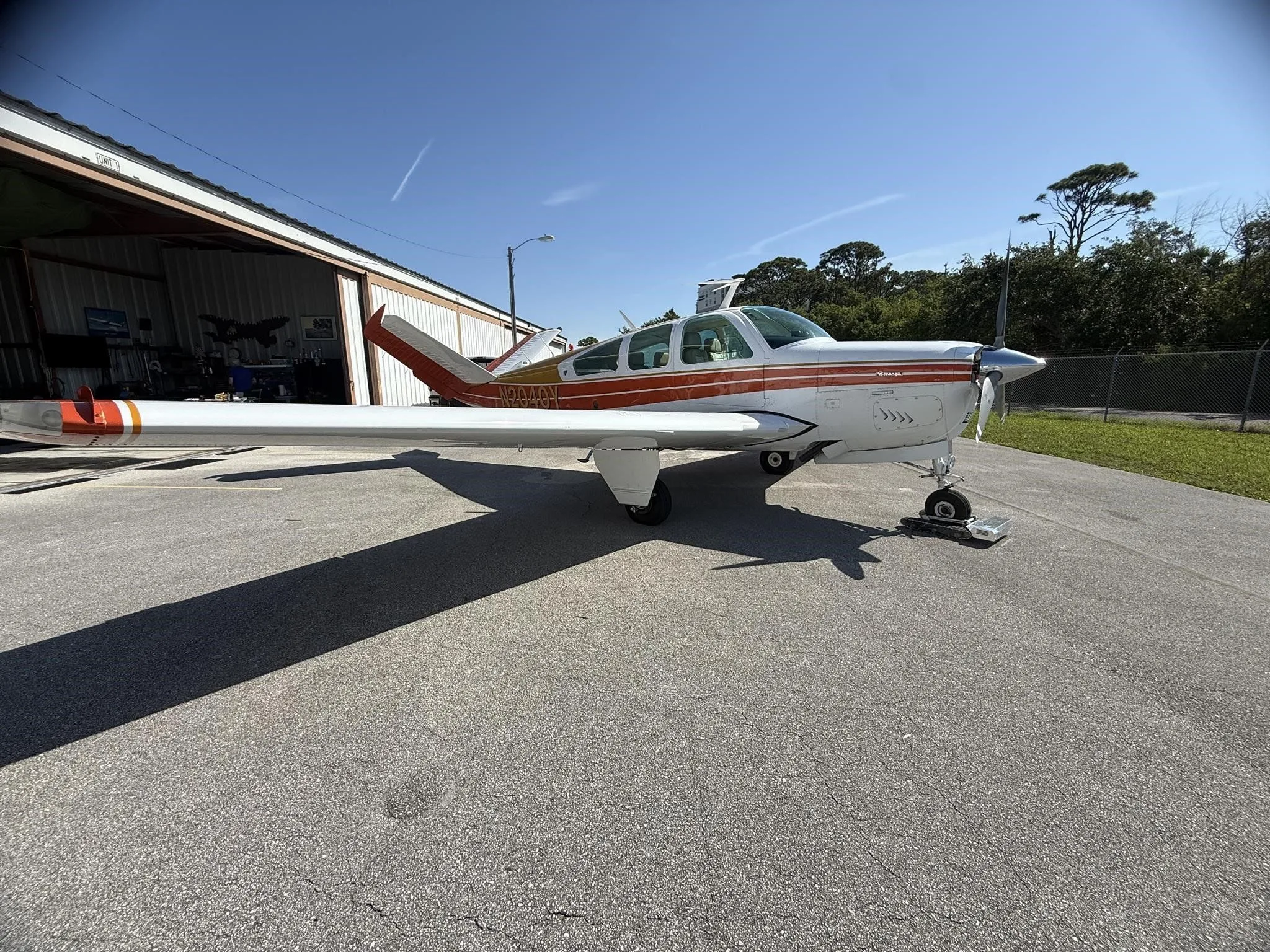 A white and orange single-engine aircraft, N2040Y, seen from the front-left, parked on an asphalt ramp.