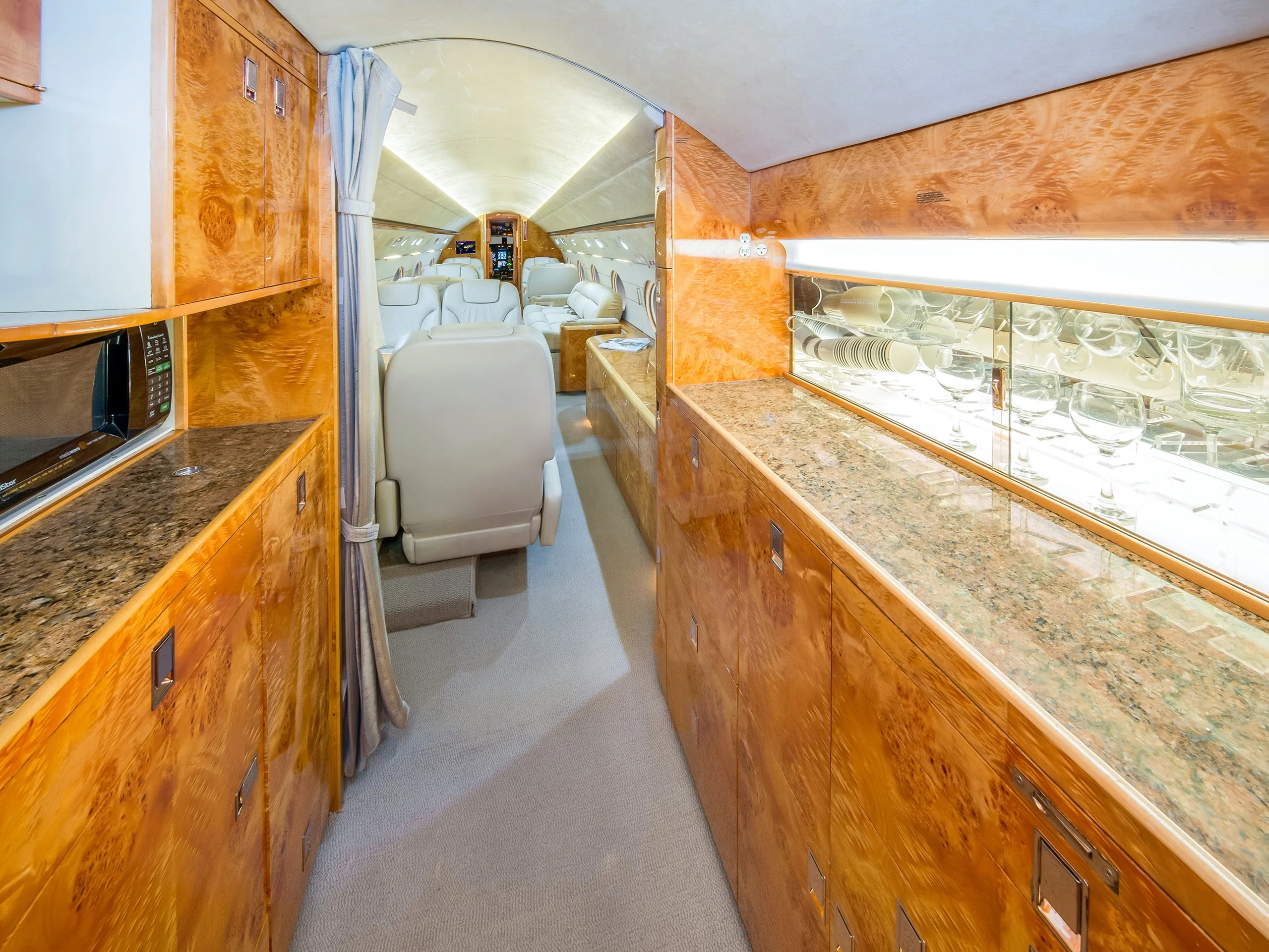 Aircraft interior with wood cabinets and cream-colored leather seats.