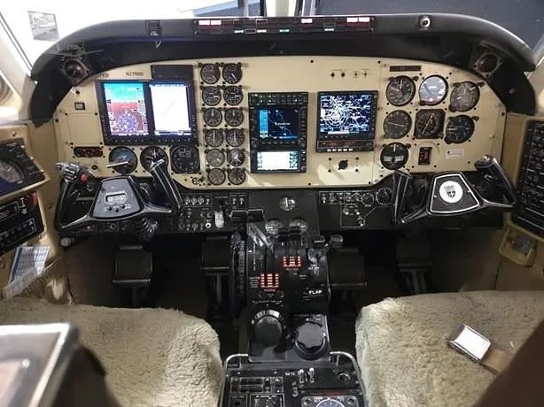 The aircraft cockpit features a complex instrument panel with multiple screens and analog gauges, along with two control yokes.