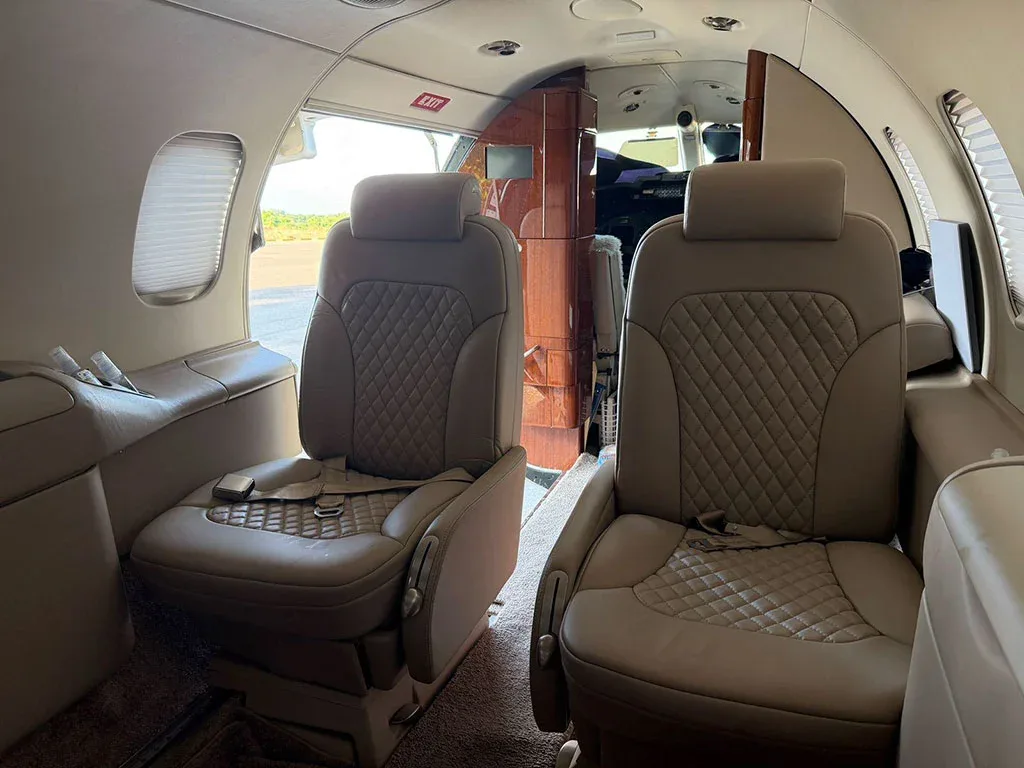 A view of the aircraft cabin with light beige quilted leather seats looking towards the cockpit area.