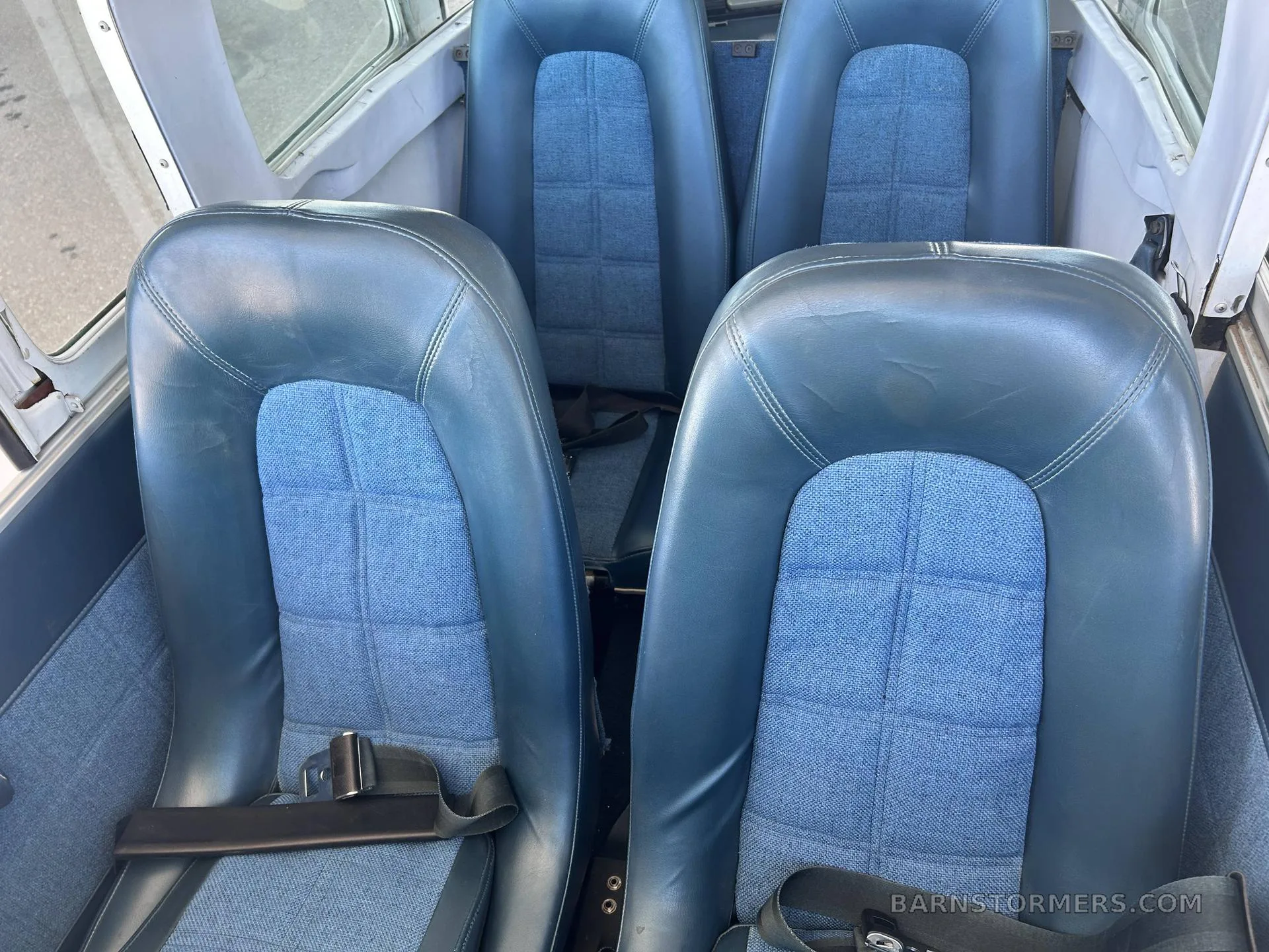 Four blue aircraft seats with fabric inserts are visible in the cabin interior.